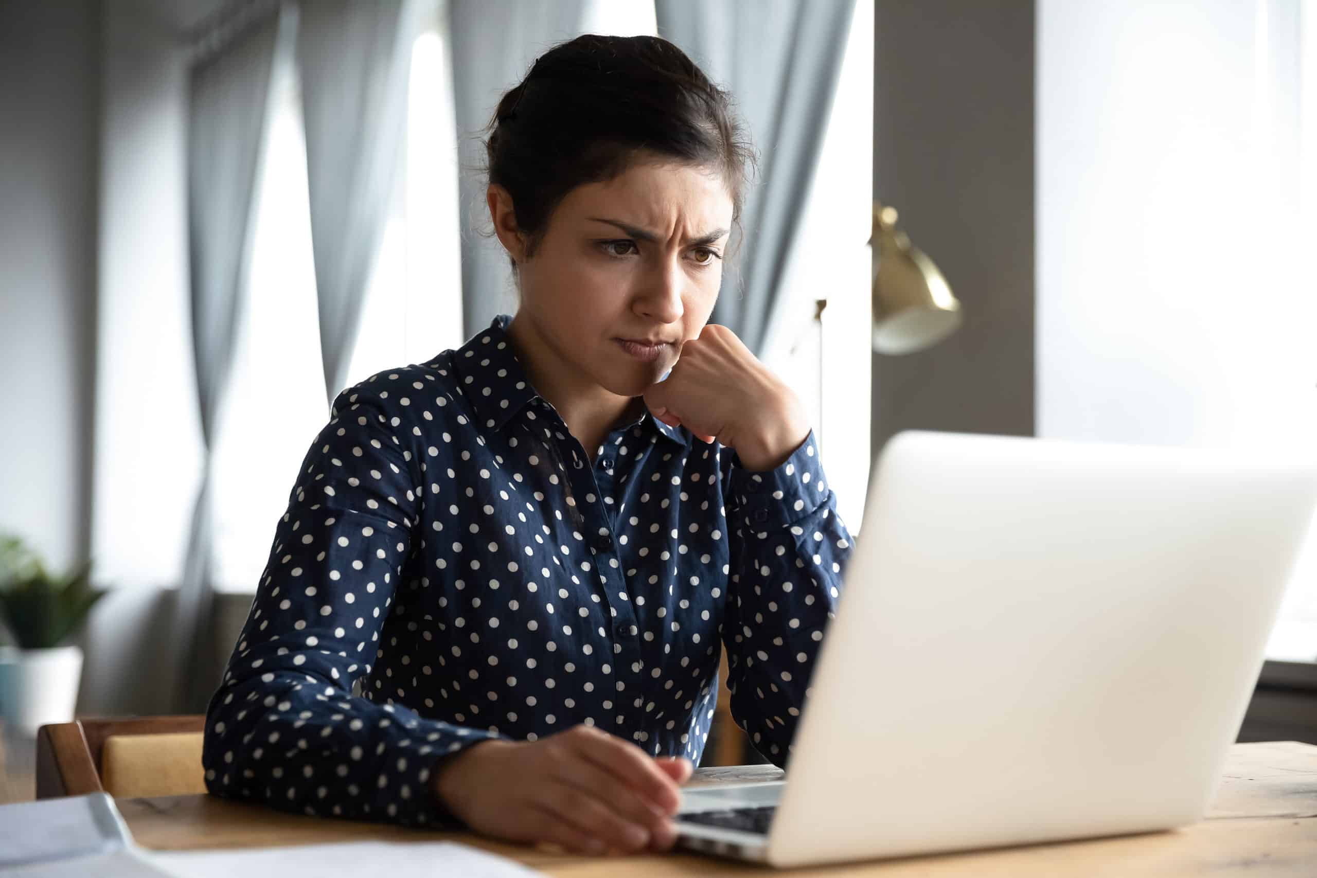concerned woman on laptop in polka dot shirt